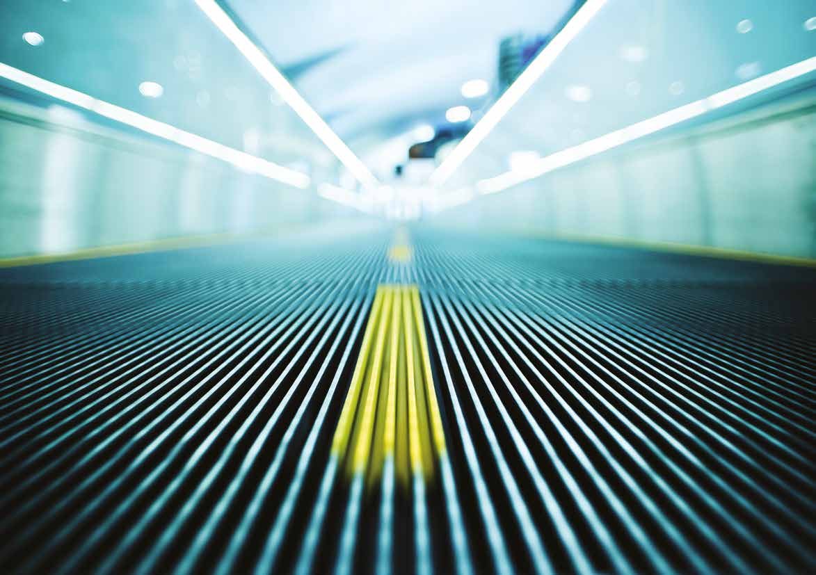 A moving walkway receding into the distance under bright ceiling lights, with a yellow guide line running down the center.